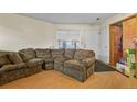 Cozy living room area showcasing a sectional sofa, laminate floors, and a sunlit window with white blinds at 17034 E Tennessee Dr # 105, Aurora, CO 80017