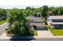 Two-story home showcases a neutral exterior, balcony, and two-car garage, surrounded by mature trees and a well-kept lawn at 7118 W Elmhurst Ave, Littleton, CO 80128