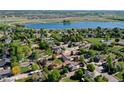 Expansive aerial view of a suburban home with mature trees, a large backyard, and a tranquil lake nearby at 2151 Burbank St, Berthoud, CO 80513