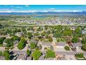 Expansive aerial shot highlighting a home in a lush neighborhood with mountain views, trees, and nearby lake at 2151 Burbank St, Berthoud, CO 80513