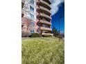 Multi-story red brick building with unique curved balconies, set against a lush green lawn at 4875 S Monaco St # 103, Denver, CO 80237