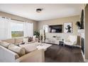 Bright living room featuring hardwood floors, a stylish fireplace, a large window with sheer white curtains, and modern furnishings at 14807 Haley Ave, Parker, CO 80134