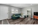 Living room features a green sectional sofa, wood-look floors, and a large mirror at 5332 Granby St, Denver, CO 80239