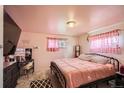 Cozy bedroom features a comfortable bed, a vanity, and lots of light through the patterned curtains at 6033 Hoyt Ct, Arvada, CO 80004