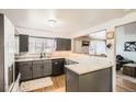 Modern kitchen featuring sleek countertops, gray cabinetry, stainless steel appliances, and a serving hatch at 6033 Hoyt Ct, Arvada, CO 80004
