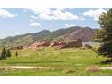 Wide shot of Red Rocks from a well-maintained backyard with a large grassy area at 27 Tamarade Dr, Littleton, CO 80127