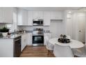 Modern kitchen featuring white cabinetry, stainless steel appliances, granite countertops, and an adjacent breakfast area at 46558 Avery Ln, Bennett, CO 80102