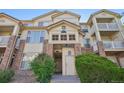 The brick and siding of a multi-story condo building entrance boasts curb appeal and meticulous landscaping at 5726 N Genoa Way # 301, Aurora, CO 80019