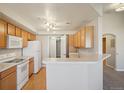 Bright kitchen featuring wooden cabinets, white appliances, and a convenient breakfast bar at 5726 N Genoa Way # 301, Aurora, CO 80019