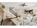 Open-concept living room features hardwood floors, a fireplace, and staircase to the upper level at 15980 Pikes Peak Dr, Broomfield, CO 80023