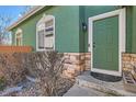 Inviting entrance with a green front door, stone accents, and manicured landscaping at 2116 W 101St Cir, Thornton, CO 80260