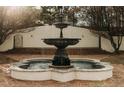 A large, tiered fountain sits centered on a brick patio, backed by a white fence and bare trees at 3 Carriage Brook Rd, Cherry Hills Village, CO 80121