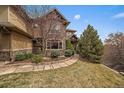 A stone facade accentuates this two-story home with manicured lawn and natural landscaping at 1159 Buffalo Ridge Rd, Castle Pines, CO 80108