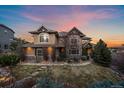 Beautiful two-story home with a stone and tan facade, manicured lawn, and meticulous landscaping at 1159 Buffalo Ridge Rd, Castle Pines, CO 80108