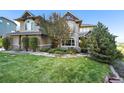 Attractive two-story home featuring a lush green lawn and mature trees at 1159 Buffalo Ridge Rd, Castle Pines, CO 80108