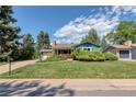 This property has mature trees, a green lawn, and the home is painted in a complementary blue and tan color palette at 815 Hoyt St, Lakewood, CO 80215