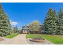 Charming home with lush green lawn, beautiful trees, and a circular landscaped flower bed in the front yard at 73 N Ranch Rd, Littleton, CO 80127