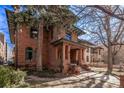 Charming exterior view of a brick home featuring mature trees, well-kept landscaping, and stone accents at 1034 N Logan St # 2W, Denver, CO 80203