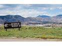 6th Avenue West II sign on a grassy hill with the town and mountains in the background under a blue, partly cloudy sky at 412 Gladiola St, Golden, CO 80401