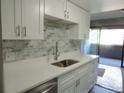 The bright kitchen features white cabinetry, marble backsplash, stainless steel dishwasher and access to the deck at 9887 E Peakview Ave # F06, Englewood, CO 80111