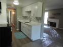 Updated kitchen with stainless steel dishwasher, white cabinets, marble backsplash and view to living area at 9887 E Peakview Ave # F06, Englewood, CO 80111