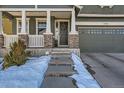 Charming home entrance with stone accents, covered porch, and a two-car garage at 10935 Valleybrook Cir, Highlands Ranch, CO 80130