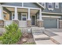 Inviting front porch featuring stone pillars and a gray front door, enhanced by manicured landscaping at 10935 Valleybrook Cir, Highlands Ranch, CO 80130