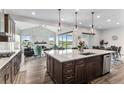 Open kitchen view showcasing the large island, pendant lighting, stainless steel appliances, and hardwood flooring at 5736 Cadara Way, Parker, CO 80134