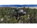 Overhead capture showcasing the home's green roof, stone chimney, and surrounding forest at 5090 S Perry Park Rd, Sedalia, CO 80135