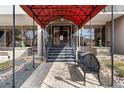 Elegant building entrance with a red awning, stone pathway, landscaping, and a bench at 2 Adams St # 608, Denver, CO 80206