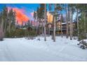 Distant exterior view of multi-story home with deck and wood and stone facade, surrounded by tall pine trees in winter at 127 Marks Ln, Breckenridge, CO 80424