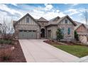 Inviting stone-and-siding house featuring a two-car garage and a landscaped front yard with a long driveway at 634 Hiddenbrook Ct, Highlands Ranch, CO 80126