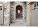 Close-up of the front door with a stone archway and brick accents at 634 Hiddenbrook Ct, Highlands Ranch, CO 80126