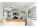 Updated kitchen with stainless steel appliances, light gray cabinets, butcher block, and window view at 13244 Quivas St, Denver, CO 80234