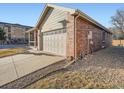 The side exterior view of the property includes a long driveway and a brick and siding facade at 11197 W 64Th Pl, Arvada, CO 80004