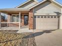 Charming single-Gathering home featuring a brick facade, covered porch, and a two-car garage at 11197 W 64Th Pl, Arvada, CO 80004