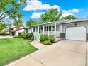 Charming single-story home featuring a well-manicured lawn, flower garden, and covered front porch at 6943 Ingalls St, Arvada, CO 80003