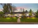Stunning single story home with warm interior lights, mature trees, and a walkway to the front door at twilight at 21 Fairway Ln, Littleton, CO 80123