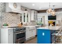 Charming kitchen featuring a stainless steel oven, farmhouse sink and a blue island with barstool seating at 21 Fairway Ln, Littleton, CO 80123