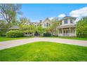 Charming two-story home featuring a manicured lawn, circular driveway, and a welcoming front porch at 980 E Tufts Ave, Cherry Hills Village, CO 80113