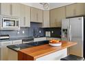 Modern kitchen with stainless steel appliances, black countertops, and wood breakfast bar at 1738 N Franklin St # 2B, Denver, CO 80218