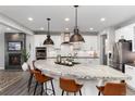Modern kitchen featuring a large island with pendant lighting, stainless steel appliances, and sleek white cabinetry at 10580 Greycliffe Dr, Highlands Ranch, CO 80126