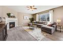 Cozy living room with a fireplace, neutral tones, plush carpet, and a large window for natural light at 12017 Triple Crown Dr, Parker, CO 80134