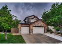 Beautiful home exterior with a three-car garage, stone accents, solar panels, and lush green lawn at 8657 Aberdeen Cir, Highlands Ranch, CO 80130