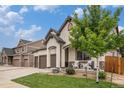 Home featuring a two-car garage, accented stone and front porch with seating and landscaping at 11511 E 118Th Ave, Commerce City, CO 80640