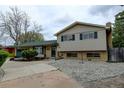 Charming home featuring an attached two-car garage, mature trees, and brick and vinyl siding at 11310 W Center Ave, Lakewood, CO 80226