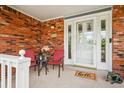 Inviting front porch with brick accents, outdoor seating, and a decorative 'hello' welcome mat at 8732 W Arbor Ave, Littleton, CO 80123