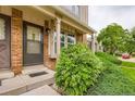 Inviting front entrance with brick facade, covered entry, and lush, green landscaping at 9672 W Chatfield Ave # C, Littleton, CO 80128