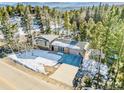 An aerial shot capturing a home and its driveway amid a forest of trees and snowy landscape at 30633 Kings Valley Dr, Conifer, CO 80433