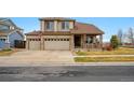 Traditional home boasting a three-car garage, covered porch, and well-maintained front lawn at 10741 Idalia Way, Commerce City, CO 80022